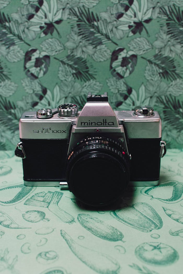 Classic Minolta SRT100X camera with green floral backdrop.
