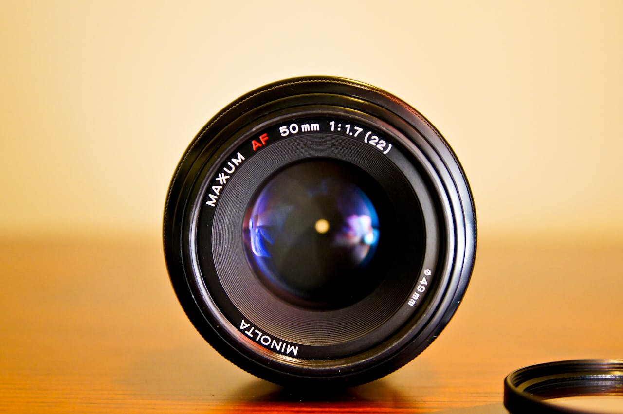 Detailed close-up of a Minolta 50mm camera lens on a wooden surface.